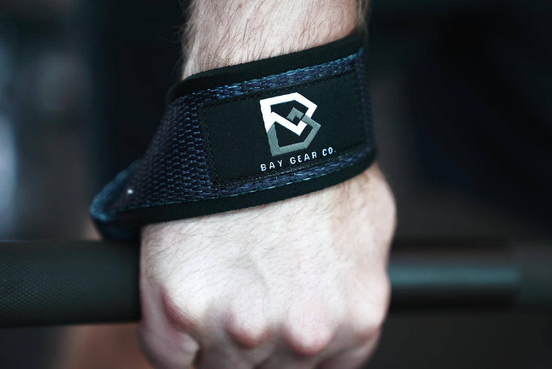 Padded loop lifting straps wrapped on a loaded barbell at deadlift setup