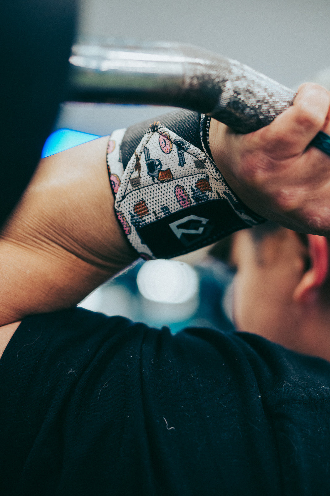 Lifter wearing Wild west donuts wrist wraps over the wrist joint while gripping a barbell for bench press